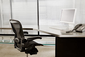 a room with a desk and chair in front of a window