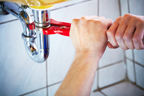 hands fixing a faucet with a wrench